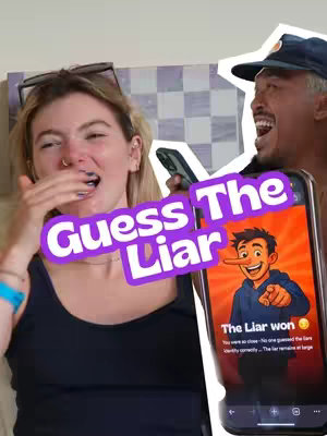 The cover image features a woman reacting to a game on the background, covering her mouth in apparent surprise. Beside her, a man is laughing and shows a mobile phone with an app interface displaying a game called "Guess The Liar", which shows a cartoon character with a long nose. The text overlay 'Guess The Liar' is centered over the image.