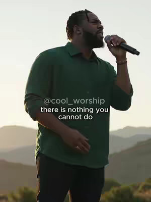 A medium shot of a Black man singing with a microphone in hand, set against a backdrop of a mountain range at sunset. The man is wearing a green shirt, and text overlay says "there is nothing you cannot do".