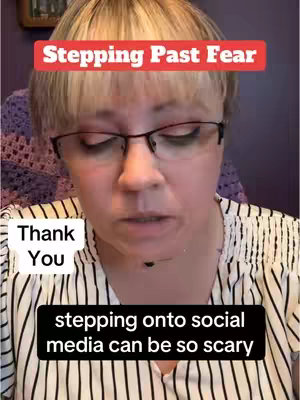 A selfie-style video cover image. The main subject is a woman with fair skin and short, light-colored hair wearing glasses. She has a neutral expression and is looking slightly down. Overlaid on the image are rectangular text boxes: one in a red banner at the top that says 'Stepping Past Fear' and one in black at the bottom that reads 'stepping onto social media can be so scary'. A smaller white text box states, 'Thank You'. The background is a bit blurred to put focus on the woman.