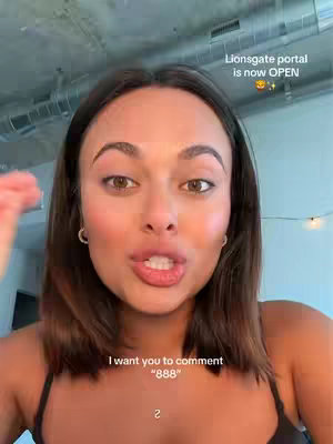 A close-up shot features a woman with deep brown eyes and medium-length brunette hair. She's wearing minimal makeup, and the shot emphasizes her face and upper chest. The background includes a glimpse of a room's interior.