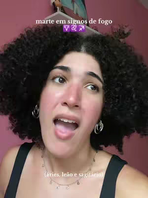 A woman with curly black hair and hoop earrings looks up and to the right with her mouth open. She wears a black top and a necklace. Text overlays appear above her head and near the bottom of the frame.