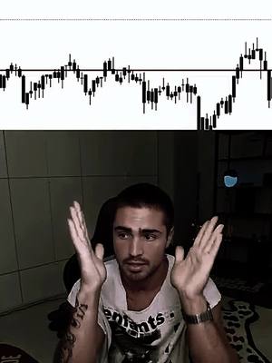 The image shows a man with dark hair and a beard looking directly at the camera with a concerned expression, raising his hands in front of him, as if in disbelief or questioning. Above him is a line graph on a white background, suggesting a financial or trading context. The man is wearing a white t-shirt with graphic text and a watch on his wrist, giving an impression of casual attire in a non-descript setting.