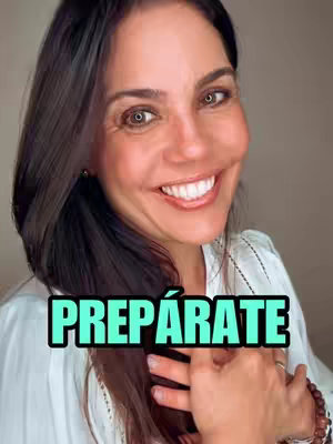 A smiling woman with long dark hair and brown eyes is the central focus. She is wearing a white top and holding her hands near her chest. Overlayed on the image, in large, green font, is the word 'PREPÁRATE'. The background has a soft, blurred aesthetic adding a warm tones to the scene.