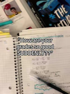 The image presents an open notebook with handwritten notes and equations spread across the pages. A black pen lies across the notebook. In the background, there's a stack of books and pages. Overlayed on the notebook is the white text: “How are your grades so good SUDDENLY??”. The top of the image depicts a photo of a person holding a balloon.