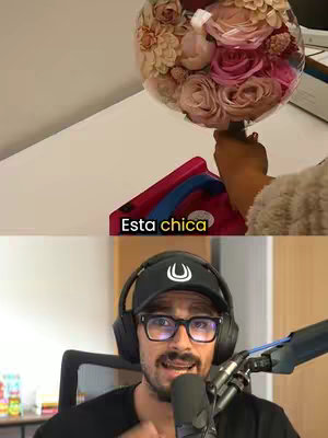 The image is a split screen; the top shows a close-up of a person holding a bouquet of flowers inside a transparent balloon, with a red box partly visible in the foreground and a table. Text that reads 'Esta chica' overlays the image. The bottom half of the image features a man wearing a black cap, glasses, and headphones, sitting in front of a microphone, seemingly speaking to the camera.