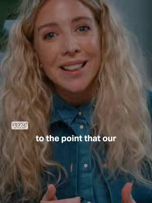 A woman with long, wavy blonde hair is seen in a medium shot, smiling and looking directly at the viewer, her expression is warm and inviting. She is wearing a blue denim shirt, with the top button undone. The background is slightly blurred, suggesting an interior setting. A small logo with the text "verse" in a white, rounded rectangle is in the bottom left corner. Text overlay is present at the bottom of the image.