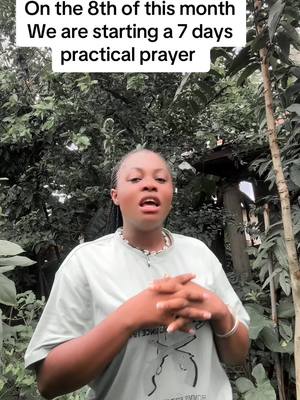 A woman is standing in front of a dense green background of foliage. She has her hands clasped in front of her. Above her head, text in white letters says, 'On the 8th of this month, We are starting a 7 days practical prayer'.