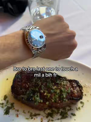 A cover image showing a person's wrist with a silver watch and a meal of steak on a plate below. The watch has a blue face. The plate holds the steak, topped with what appears to be herbs and sitting on an oily base next to a fork. The background includes a glass of water and a white tablecloth.