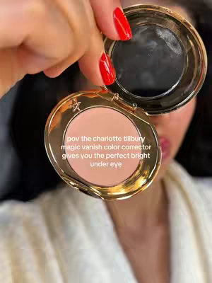 A close-up shot of a person's face with red nail polish holding an open, gold-rimmed compact mirror over their face, revealing a light pink cosmetic product inside. The hook text is overlaid on the image.