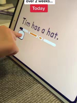 A hand is touching a tablet screen displaying text. The text reads "Tim has a hat." A progress bar is visible. In the upper-left corner, a small red box displays the word "Today". The background is a neutral color, probably a table.