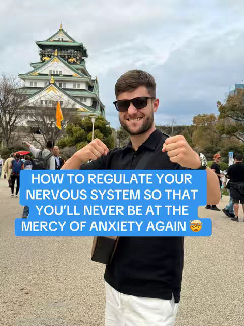 A man wearing sunglasses and a black shirt stands smiling in front of a large Japanese castle. A blue banner with white text, overlaid on the image, promotes anxiety management.