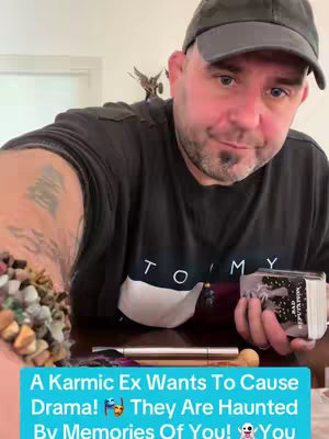 A middle-aged man wearing a dark-colored shirt, a baseball cap and holding a deck of cards and a pen, appears to be presenting a tarot card reading. The text overlay in a vivid blue, placed at the bottom adds context to the scene.