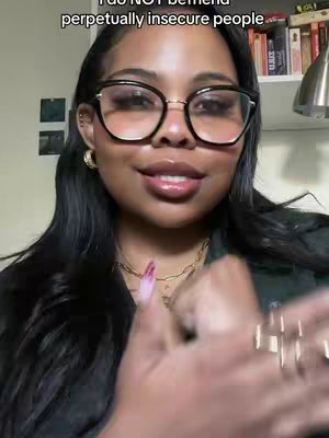 A woman with long dark hair and large-framed glasses is centered in the frame, looking towards the camera with a slight smile. She's wearing large square glasses and a gold necklace. The background is slightly blurred and includes a shelf with books and a hanging light. The text overlay reads 'I do NOT befriend perpetually insecure people'.