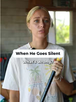 A woman with blonde hair is looking at the camera. She is wearing a light beige t-shirt and is holding a black and yellow object. There is a text overlay above the woman's head.