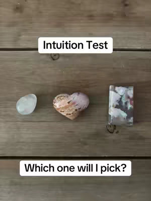The cover image shows three different crystals of various shapes displayed on a wooden surface with vertical wood planks. A text overlay says 'Intuition Test' at the top and the question 'Which one will I pick?' at the bottom.