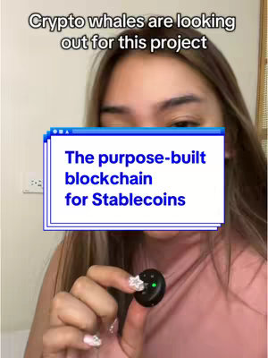 A vertical video cover image showing a light-skinned woman from the mid-chest up, holding a small rounded black device with a green light in her right hand. She is smiling, with the focus on a screen-shaped text box over her. The background consists of a neutral wall and a glimpse of a wooden frame. The image uses soft, natural lighting and a warm color palette.