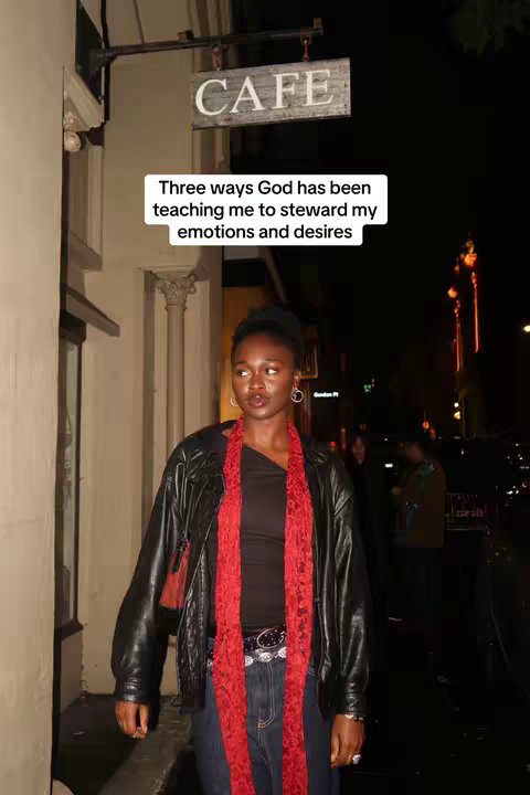 An image shows a woman standing in front of a cafe at night. The woman is wearing a black leather jacket over a black top, a red scarf, blue jeans, and a belt with a silver buckle. The cafe sign reads "CAFE". A text overlay says "Three ways God has been teaching me to steward my emotions and desires."