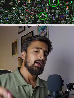 A cover image featuring a man in a green shirt in front of a screen displaying cryptocurrency data. The screen shows price changes for various crypto assets in a circular format. The man is speaking into a microphone. The background includes a wall and pictures.