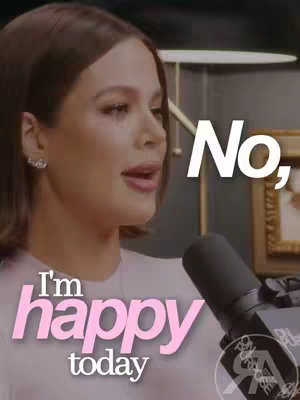 A woman is centered in the frame, looking towards the left, speaking or singing into a microphone. The text overlays, 'I'm happy today' with the words 'I'm' and 'today' in a light pink, and 'happy' in larger, darker pink font. The background is a subtly lit room with a dark background and a glimpse of gold-framed artwork. A microphone is positioned in the lower right, slightly obscuring the text.