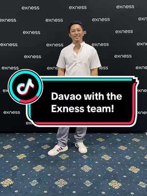A man in a white shirt and grey pants smiles, standing in front of a repeating "exness" pattern on a dark background. A TikTok frame at the bottom contains text that says "Davao with the Exness team!". The background is a patterned carpet in shades of blue.