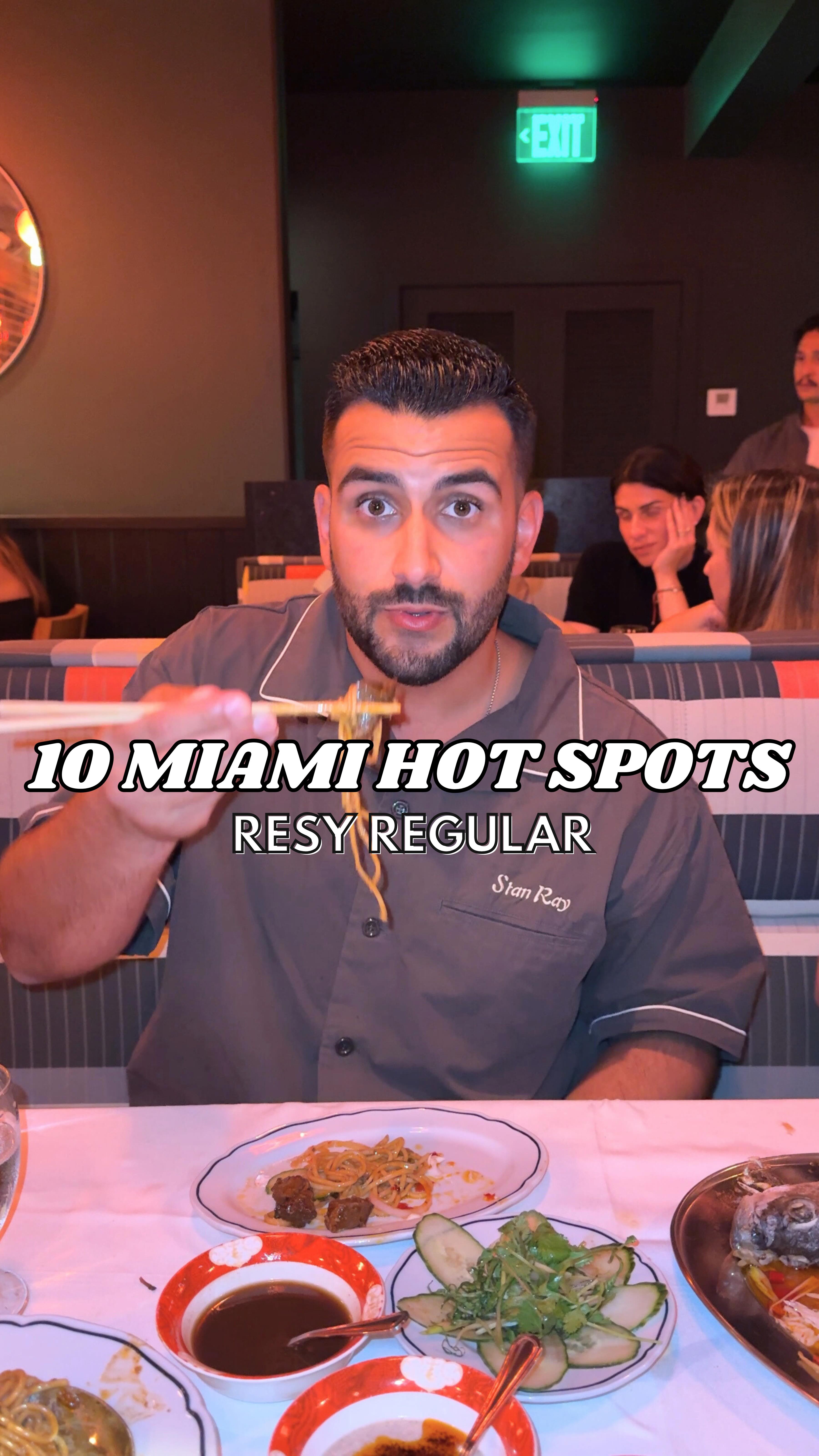 A man in a grey shirt is holding up chopsticks with noodles for a cover image of a Miami hot spots video. The text overlay reads "10 Miami Hot Spots, ResyRegular". The image is shot in a restaurant setting, with other people visible in the background.