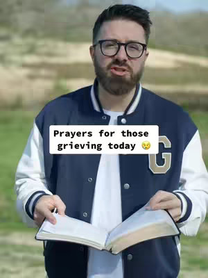 The cover image shows a man in a blue and white letterman type jacket with the letter "G" on it, standing outside. He is holding an open book. A text overlay on the cover picture on a white background with rounded corners, that reads, "Prayers for those grieving today 🥺".