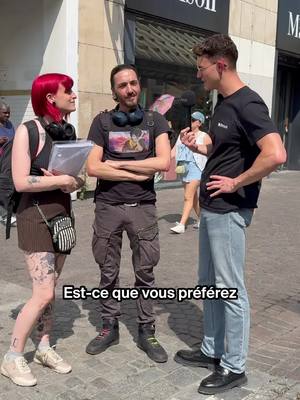 Three people are standing on a sidewalk. Two men and a woman are in frame. The woman is on the left, the first man in the middle, and the second man on the right. The woman has red hair and is holding a notebook. The man in the middle has his arms crossed. The man on the right has his hands on his hip, facing towards the two people with a smile