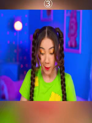A woman with long, braided pigtails looks down with a surprised expression. She's wearing a lime green t-shirt with a yellow square on the front. The background is a neon blue room with a pink couch and a round light fixture.