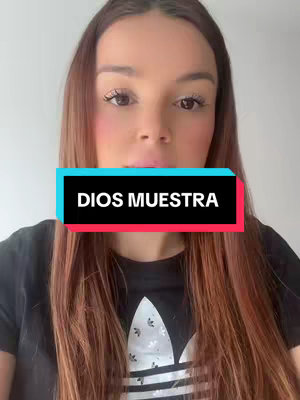 The cover image shows a person in a close-up shot, facing the camera directly. They have long, light brown hair and are wearing a black t-shirt with a white logo. A colored text overlay reading "DIOS MUESTRA" is centrally placed over their face. The background is a plain, light-colored wall, creating focus on the person and the text.