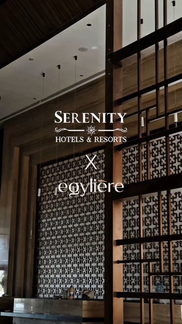 The image showcases the interior of a modern luxury hotel lobby. The composition is divided horizontally, with a dark wooden ceiling and the text overlay at the top. Below, the image features a dark wooden structure and a patterned wall with a mix of black and white geometric shapes. The overall composition is clean and minimalistic, emphasizing modern design and style.