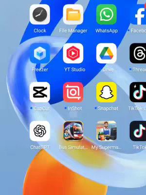 The image is a screenshot of a phone's home screen. The background has a white to light blue gradient. Several app icons are organized on the screen, including clock, file manager, WhatsApp, Facebook, Freezer, YT Studio, ChatGPT, and other apps. The overall composition is a grid-like layout of application icons against the blurred background