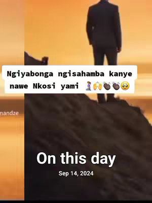 The image shows a man in a suit standing on a rock formation with his back to the camera, looking out at a sunset. Text overlays include a Zulu phrase, with emojis including praying hands, a halo, beans, and a sad face, as well as the words 'On this day' and the date 'Sep 14, 2024'. The overall composition conveys a feeling of reflection and remembrance.