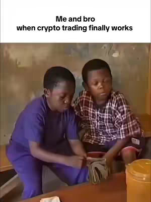 The image shows two young boys, posed indoors, likely a scene from a video. They are sitting down, with a plain wall in the background. The image has text overlaid at the top where it states: "Me and bro when crypto trading finally works."