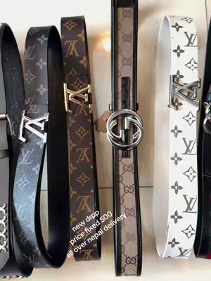 The image showcases a collection of designer belts. Several belts are presented side by side, each featuring a different pattern, color, and buckle design. The belts are likely high-end, showing recognizable logos and patterns. The lighting is even, and the composition is straightforward.