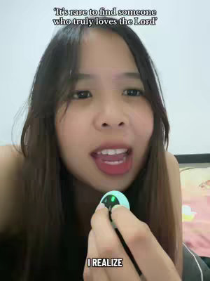A close-up shot of a young woman with long dark hair, fair skin, and light pink lipstick, holding a small, round, light blue device with a green light. The background is a plain white wall. The text overlay is in white font.
