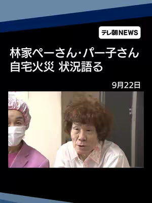 The cover image features two people in a close-up shot. One person is wearing a pink outfit and a face mask, while the other has curly hair and is wearing a patterned shirt. The background is a neutral color. Text overlays in Japanese appear at the top of the image.