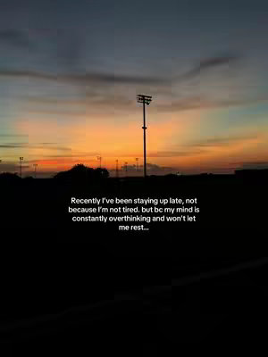 An outdoor shot depicting a sunset over a field or open area with a bright orange and yellow sky above a silhouetted foreground. A single tall light fixture stands prominently.