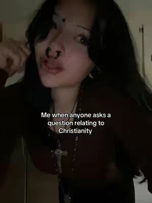 A selfie-style shot of a person with black hair, multiple piercings, and a cross necklace, looking slightly to the side behind a text overlay.