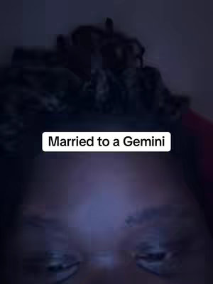 The image is a close-up shot from a low angle, focusing on the lower face of the subject, likely the eyes and the area around them. Above this focal point, there is a solid white text box that states, 'Married to a Gemini'. The background is dark, creating high contrast with the text overlay. The lighting is dim, suggesting an indoor setting.