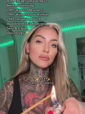 A woman with tattoos on her neck and arms holds an incense stick with fire. Text overlays include a motivational message about manifesting love and the text '222 Lionsgate Portal'. The background shows a room with green lights and decorative items.