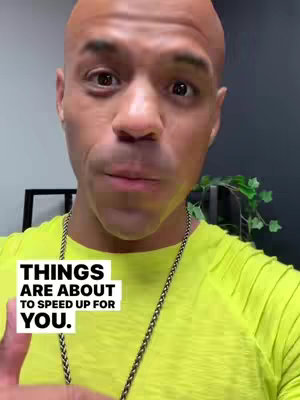 A close-up shot of a man with a bald head, wearing a lime green shirt and a chain necklace. Text in a white box overlays the image, and a hint of a leafy plant can be seen in the background. The man is looking towards the camera.