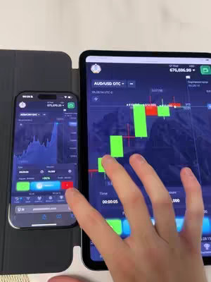 The image shows two screens and a hand. On the left is a smartphone displaying a trading app interface with a chart, accompanied by red and green buttons. On the right, a tablet shows a similar interface with a line and green bar chart. A hand is in the frame, likely interacting with the tablet screen.
