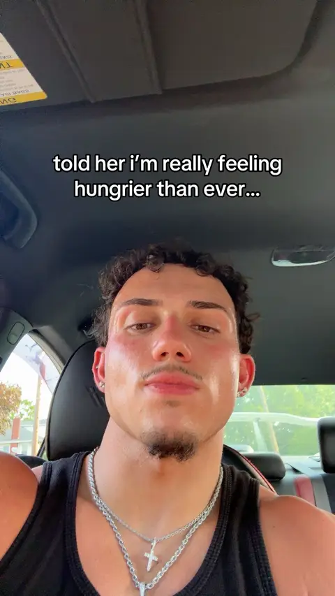 A close-up shot of a young man in a car, looking directly at the camera with a slight smile. Text overlay in the image.