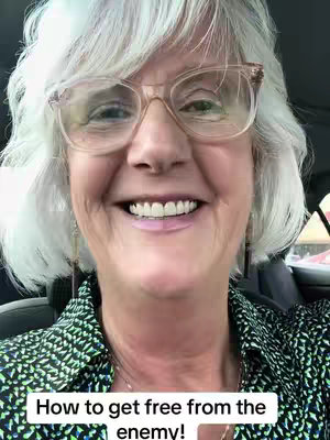 A woman with silver hair in a selfie, wearing glasses and a patterned shirt, smiling at the camera with text at the bottom.