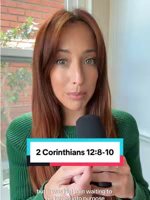A woman with auburn hair and a green sweater is holding a microphone, looking at the camera. A text overlay reads "2 Corinthians 12:8-10". Behind her is a brick wall and a window.