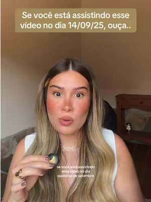 The cover image features a woman with long blonde hair, wearing a white top and a delicate necklace. She is holding a small, round object in her hand. The background is a neutral beige color, and the overall composition is a close-up shot of the woman looking directly at the camera.
