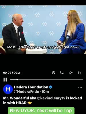 The image is a screen grab from an interview between two people. On the left, a man is wearing a black suit and tie. On the right, a woman with blonde hair in a blue blazer. The caption text overlays the video and the bottom part of the screen displays the user information and a green section saying NFA-DYOR. Yes it will be Top.