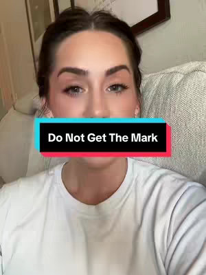 A woman with dark hair and makeup looks directly at the camera. A rectangular overlay with the text 'Do Not Get The Mark' in white is positioned over her mouth. The overall composition suggests a direct communication, perhaps a warning or message of importance. The background includes soft lighting with some artwork.