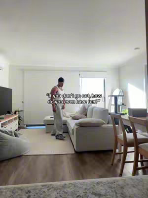 A man stands in the middle of a modern living room with natural light. The room features a white sofa, a light-colored rug, and light wood flooring. Text overlayed on the image poses a question.