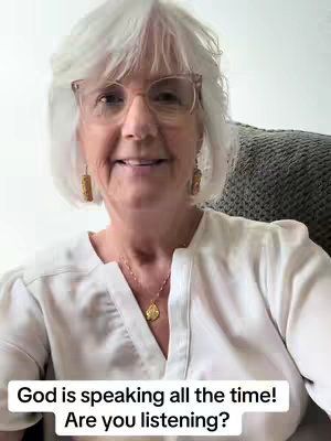 A selfie-style video featuring a senior woman with white hair, glasses, and a white blouse. The image has soft natural lighting with text overlayed at the bottom.